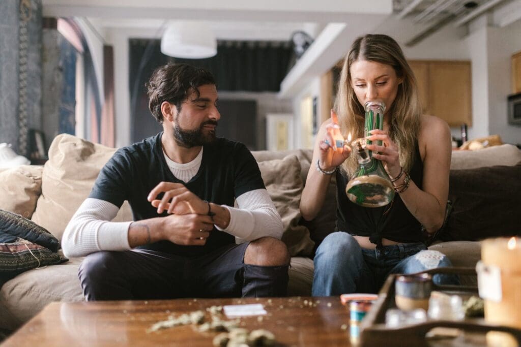 two people smoking out of a weed bong